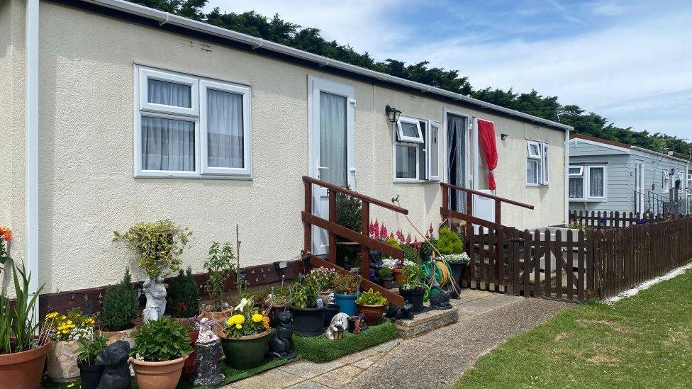 One of the rental homes on the unit. A rectangular white building. There are plants in pots outside.