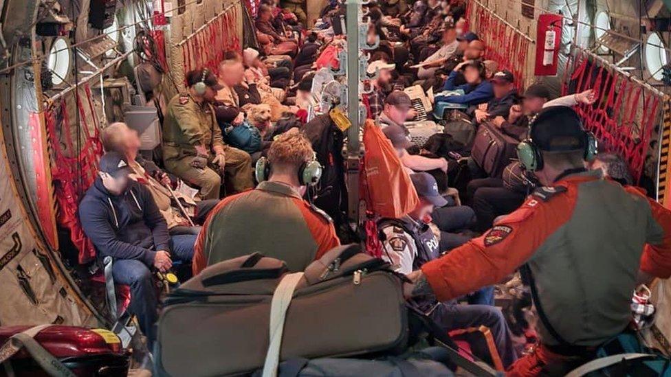 Evacuees from Fort Smith crowd into a military aircraft during an airlift