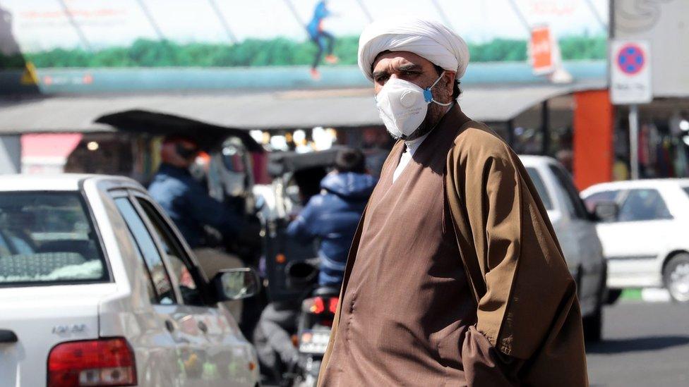 A cleric wearing a face mask walks on a street in Tehran (9 March 2020)