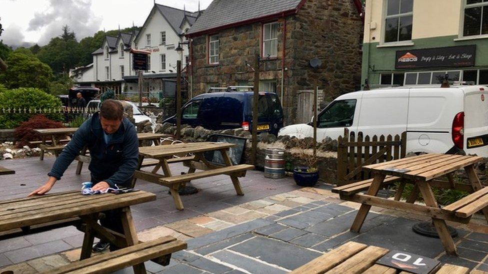 Emlyn Roberts cleans tables outside Hebog Bistro in Beddgelert, Gwynedd