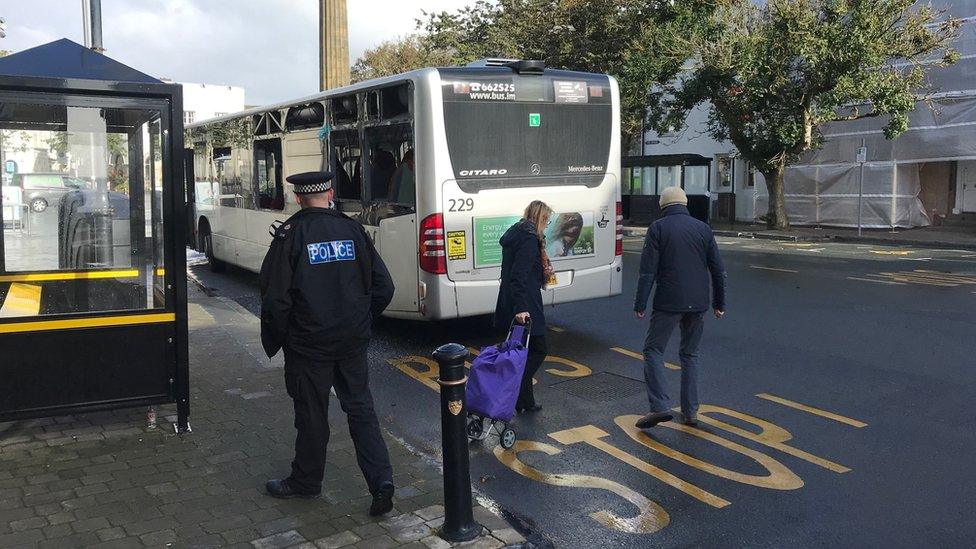 Police officer standing behind damaged bus