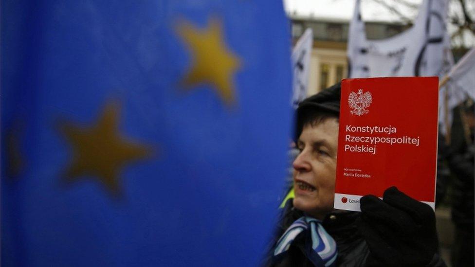 A woman holds a copy of the Polish constitution in front of the Constitutional Court during its session in Warsaw, Poland December 9, 2015