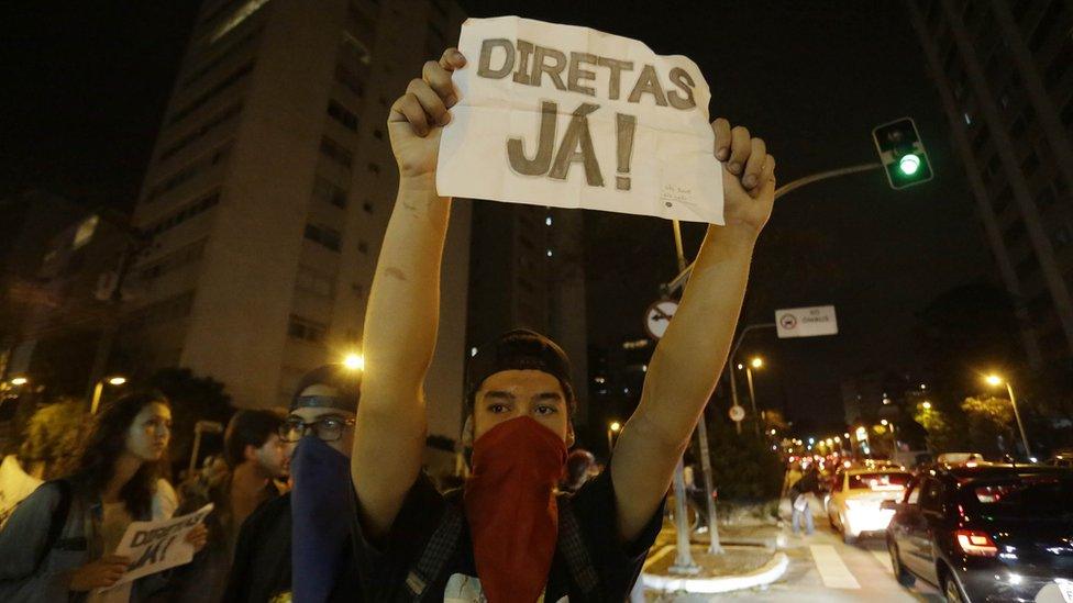 A man holds a sign that reads "Elections now" during a protest against President Michel Temer in Sao Paulo, Brazil, Sunday, Sept. 4, 2016.