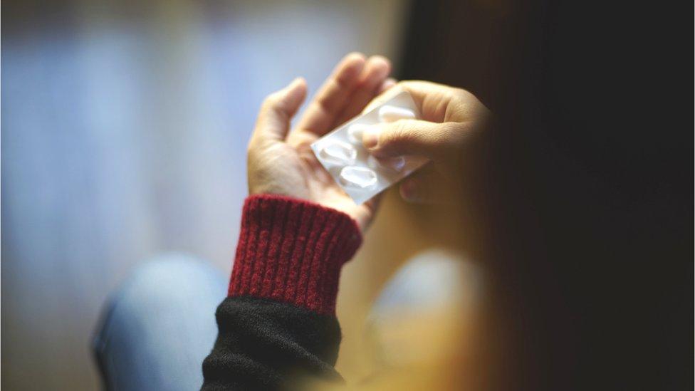 woman taking a tablet from a blister pack