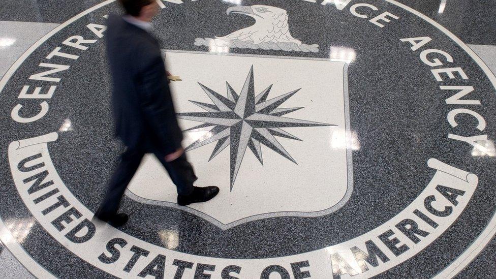 Man walking across a CIA symbol on the floor