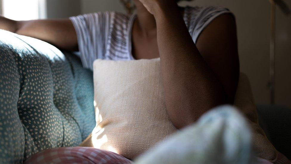 An anonymous woman holding a cushion over her stomach