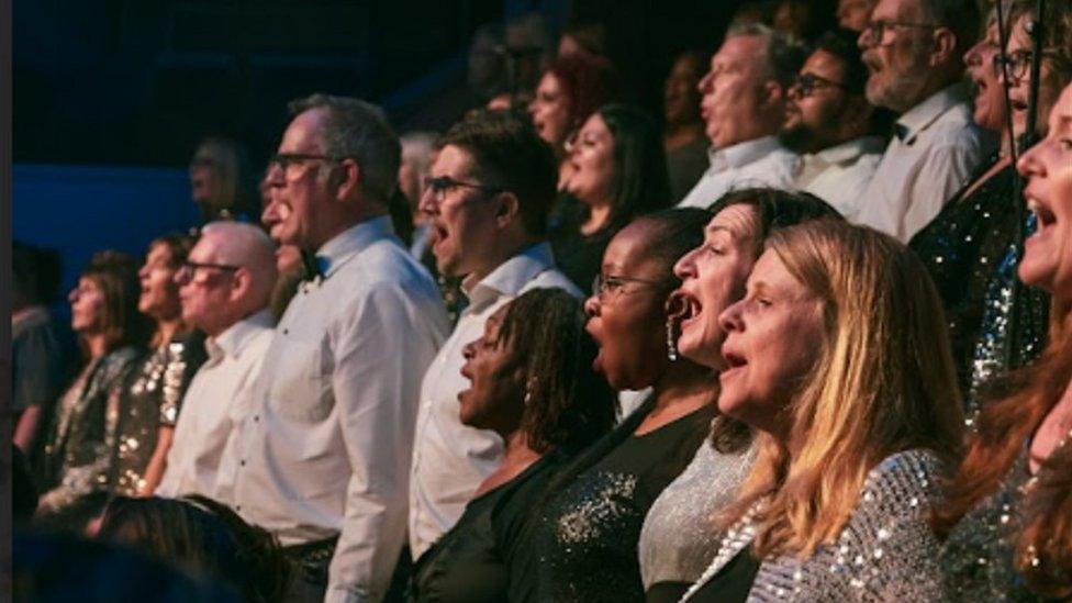 Men and women in rows, singing