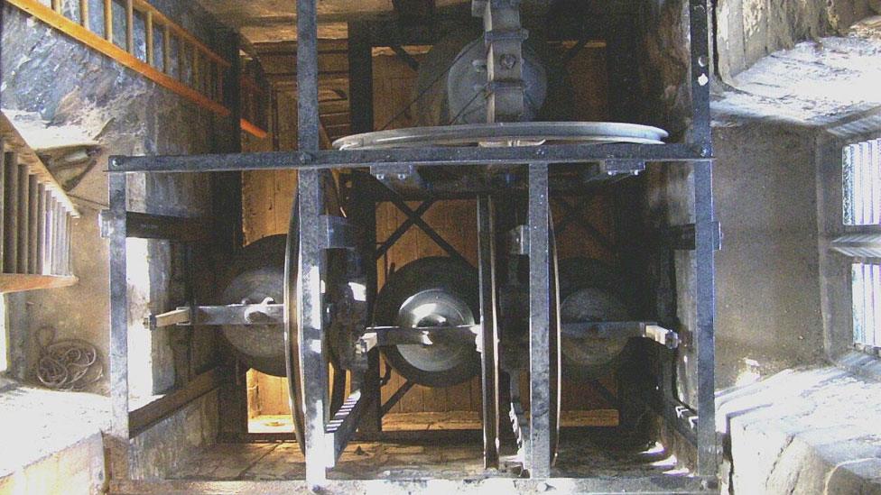 The top of four church bells hanging down in a church tower, Landbeach