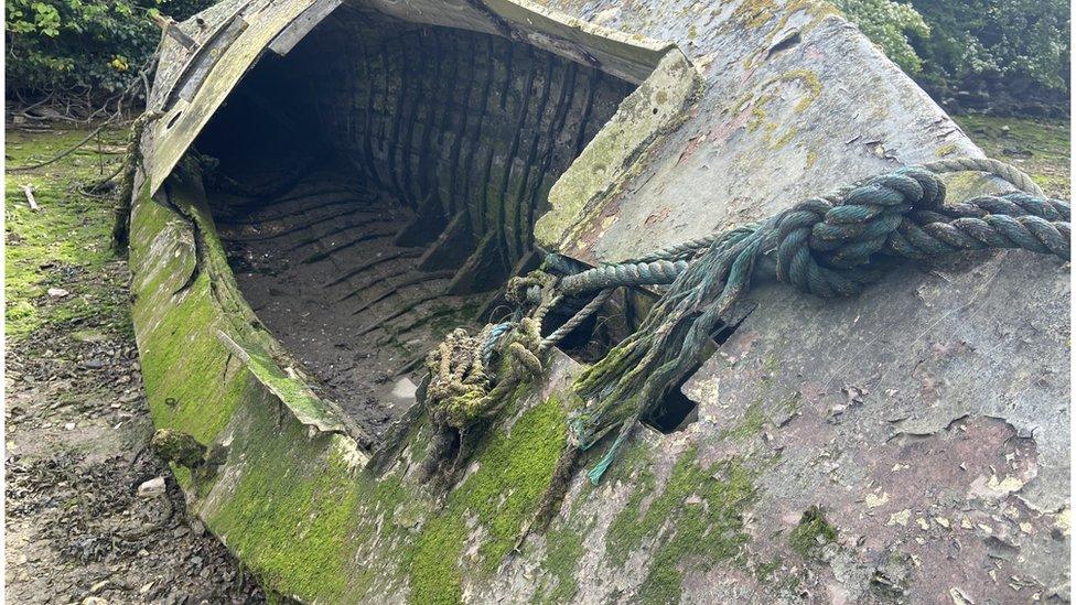 A deteriorating old boat covered in weed