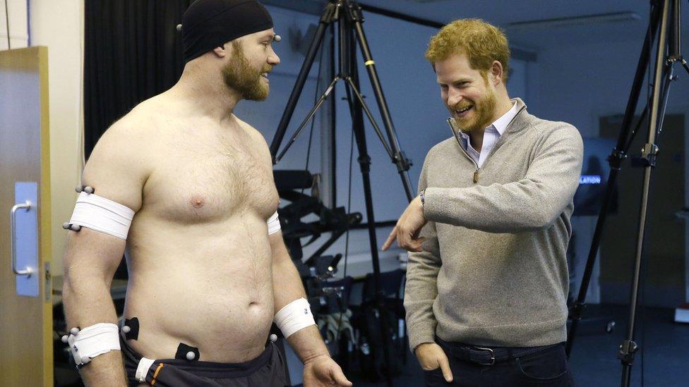 Prince Harry speaks to Matt Attwood who is covered in sensors after he demonstrated some rugby tackle research