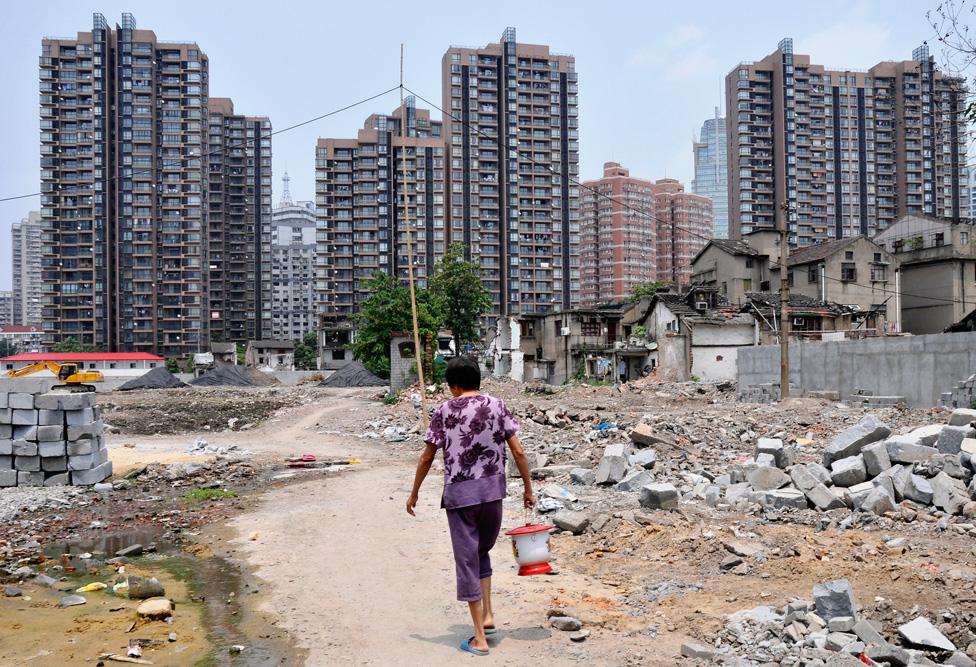 Woman walking through a construction site for more highrise housing in Shanghai, China, on 23 July 2011