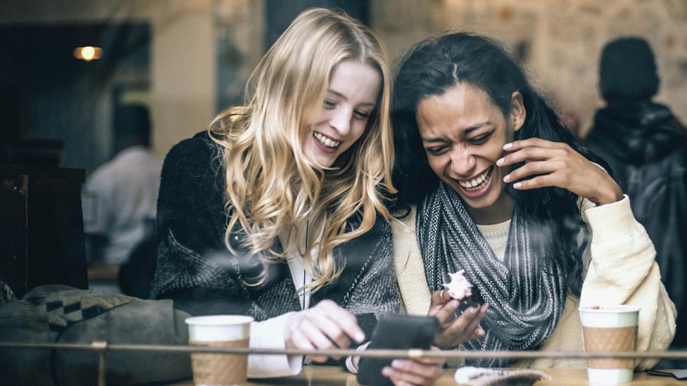 Women in a cafe looking at a phone