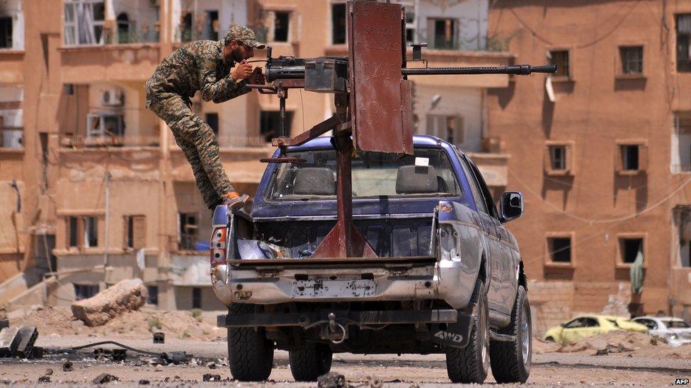 Kurdish fighter fires a heavy machine gun at Islamic State militants in the Syrian city of Hassakeh (26 July 2015)