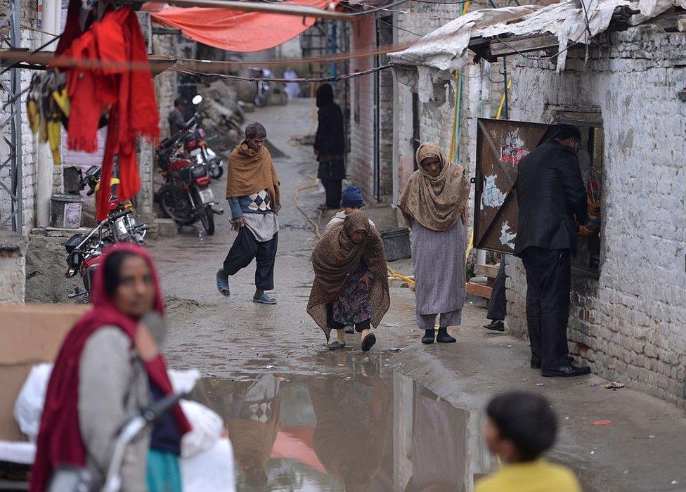 Pakistani Christians walk down a street in a slum Christian neighbourhood in Islamabad on December 10, 2015.