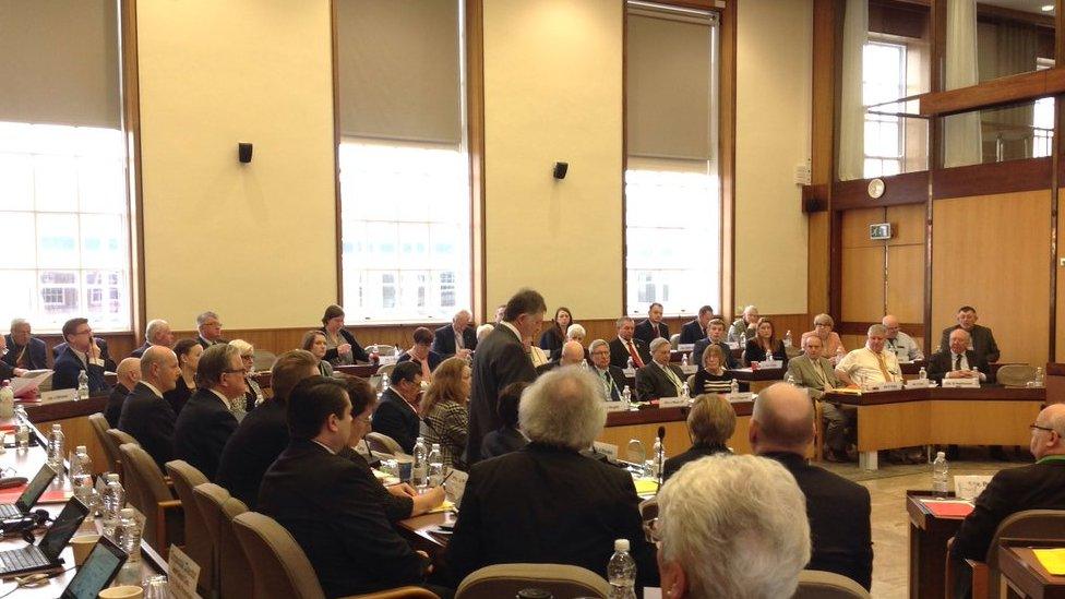 Cllr Rhodes (standing in centre) apologises at council meeting