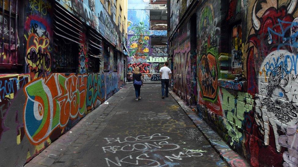 A couple look at graffiti on the walls of a laneway in Melbourne