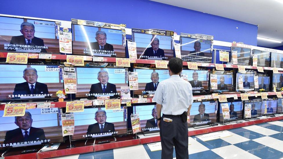 A man looks at television screens showing a speech by Japanese Emperor Akihito to the nation, are displayed at an electronic shop in Tokyo on August 8, 2016.