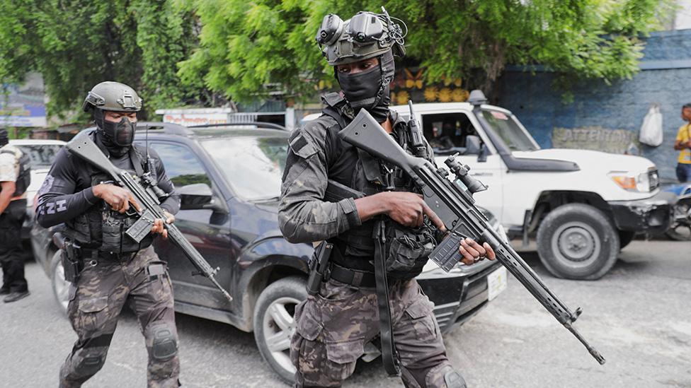 Security personnel walking and holding rifles while patrolling near the Villa d'Accueil where Haiti's transition council will be installed, on the outskirts of Port-au-Prince, Haiti April 25, 2024