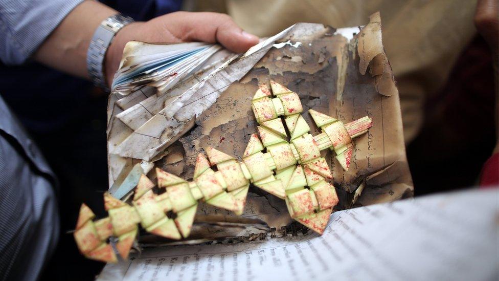 Security personnel carries a palm leaf at the scene of a bomb explosion inside Mar Girgis church in Tanta