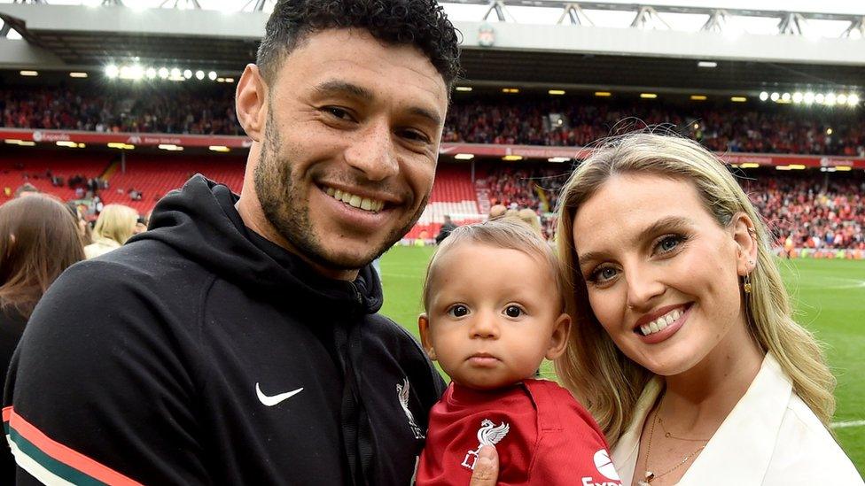 footballer alex oxlade-chamberlain with singer perrie edwards holding their son axel at the end of a premier league match