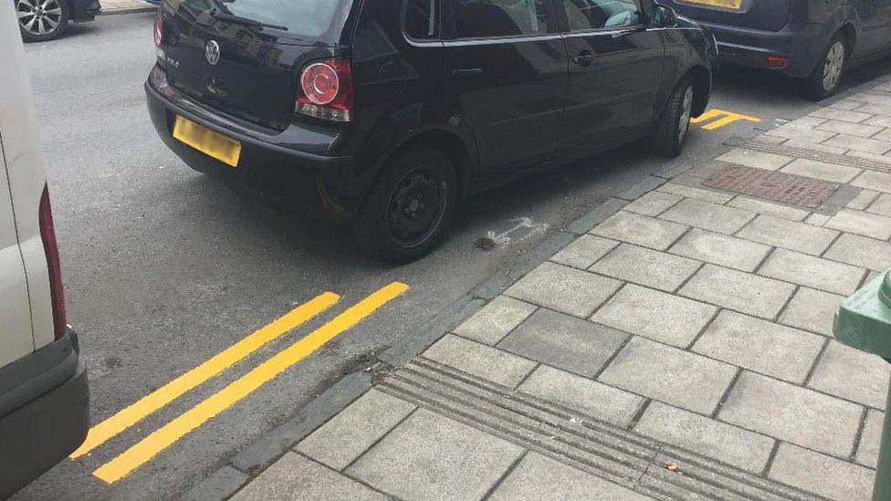 Double yellow lines painted around a black car