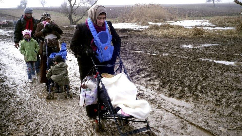 Migrants walk through thick mud as they cross the Macedonia-Serbia border in the southern Serbia (27 January 2016)