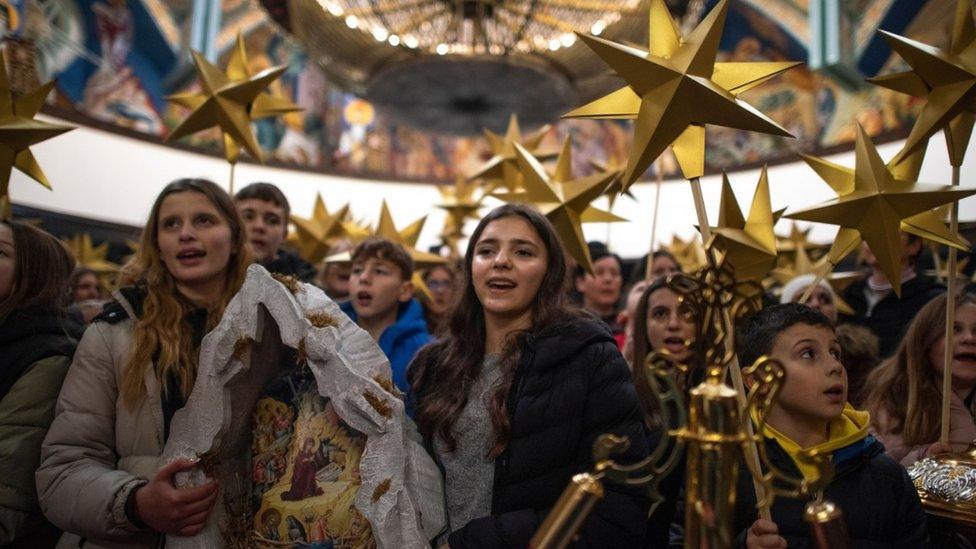 Children holding stars and a scene from the nativity