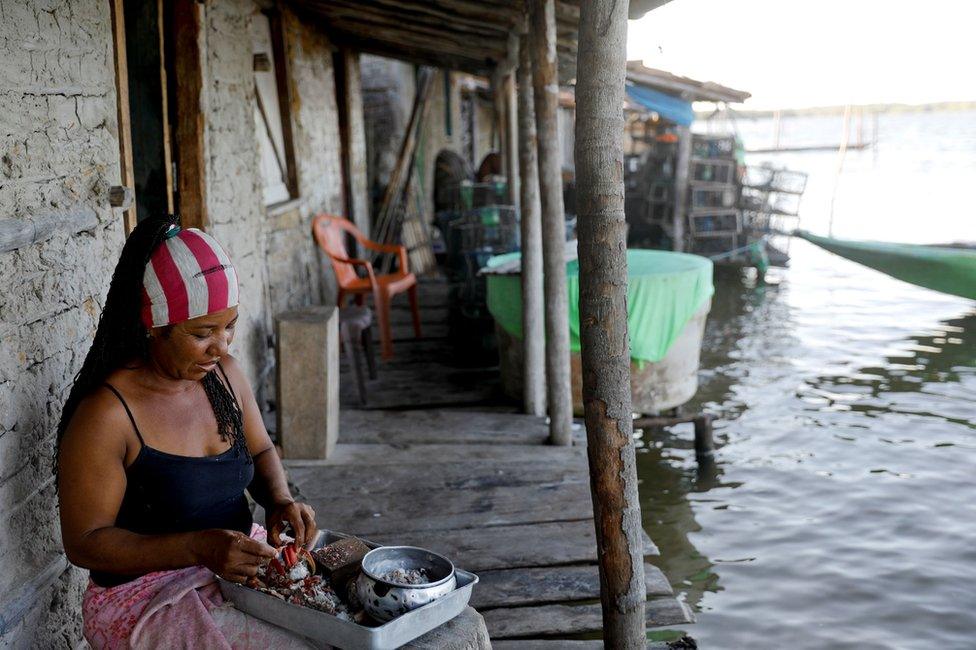 Vandeka, wife of fisherman Jose da Cruz, peels crabs