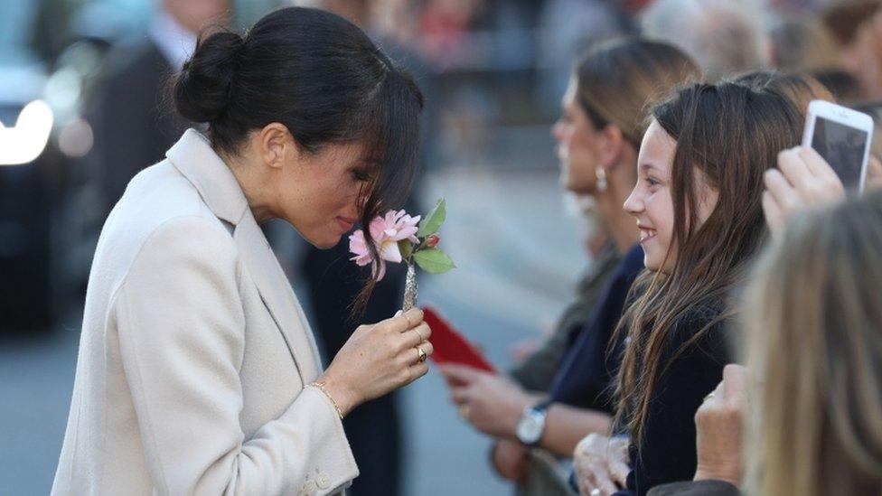 Meghan handed a flower by a girl