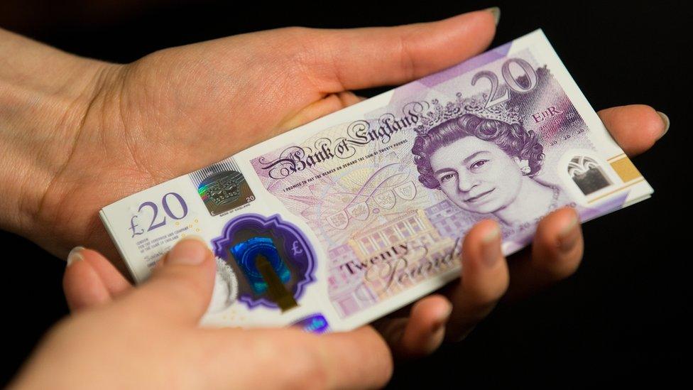 Hand holding £20 notes