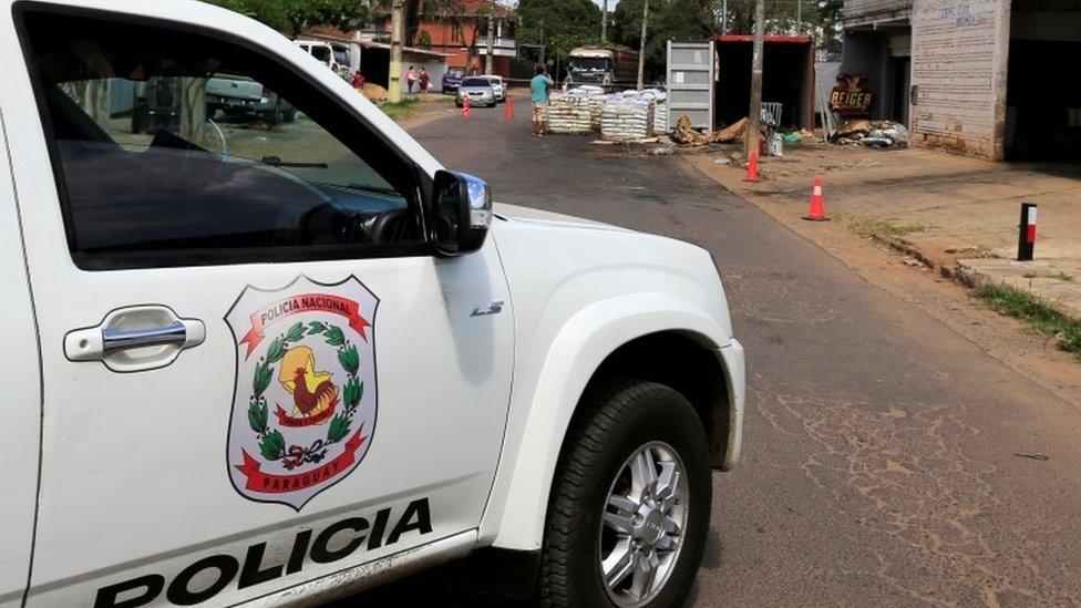 A police vehicle is seen near a container where the authorities found decomposed bodies inside a fertiliser shipment