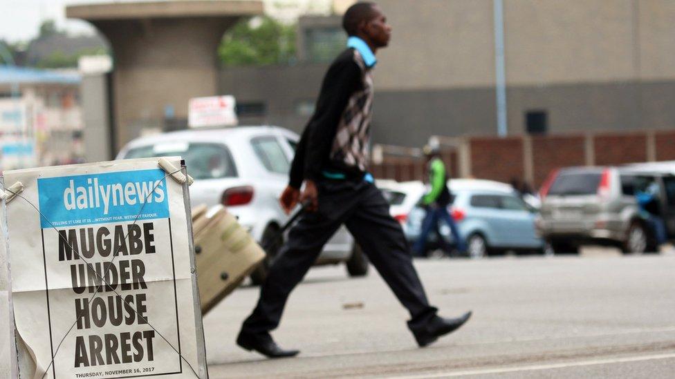 A man crosses the road in Harare behind a local newspaper poster that reads "Mugabe under house arrest".