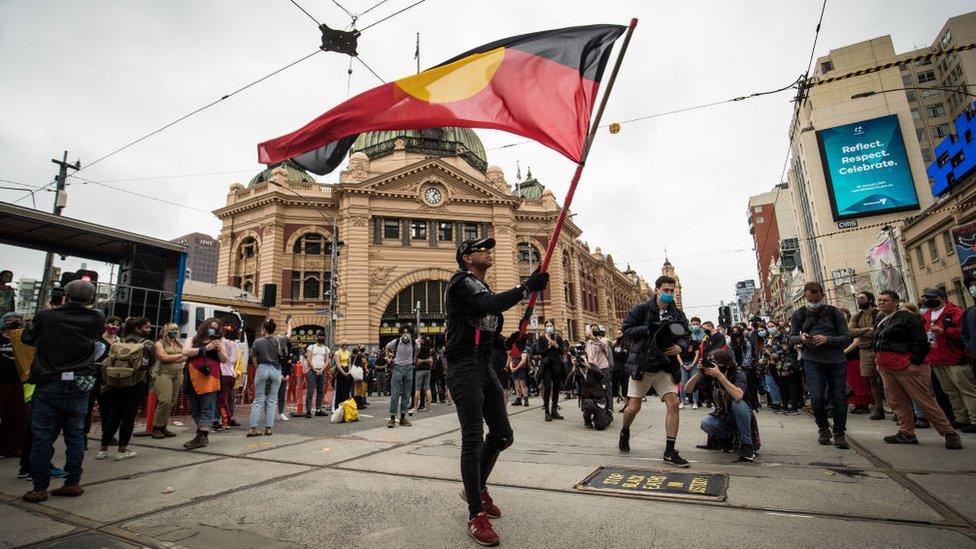 A protester hold the Aboriginal flag in central Melbourne during a mass protest on Australia Day