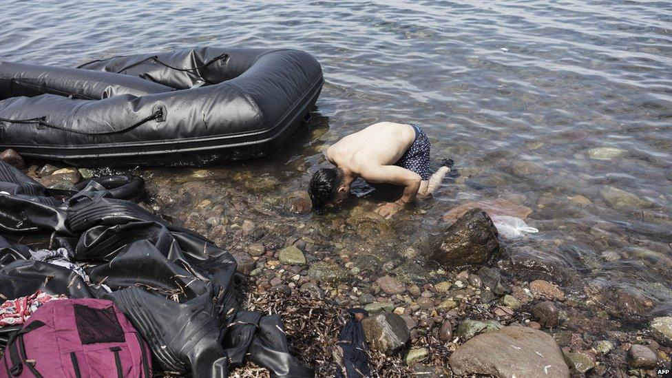 A Syrian man kisses the ground as he enters Europe