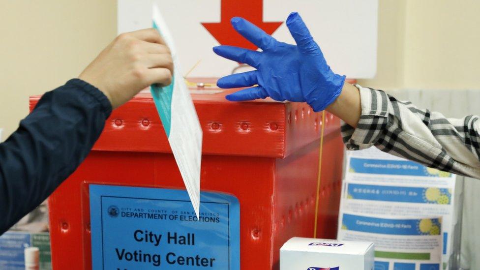 A poll worker directs a voter to a ballot box at a polling site at San Francisco City Hall on Super Tuesday in San Francisco, California, USA,