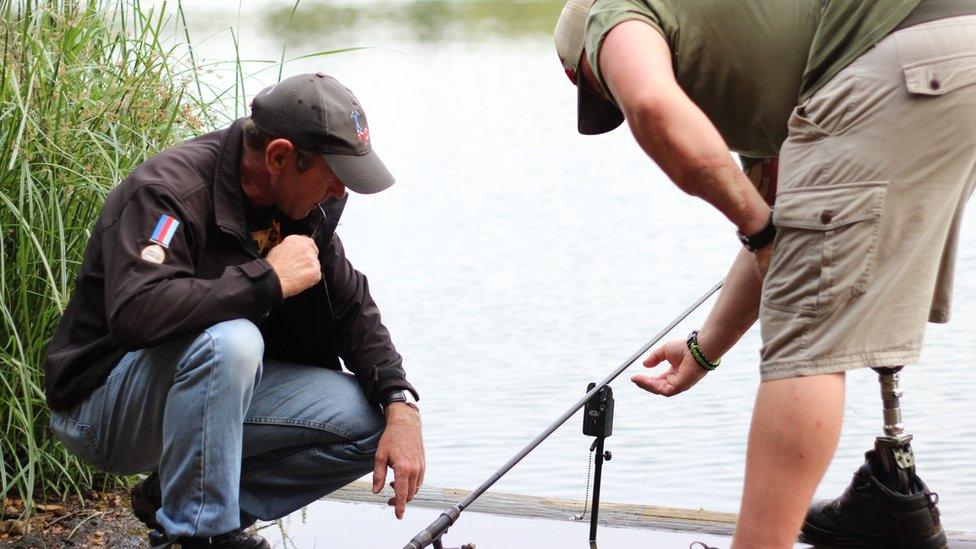 Fishermen next to a lake and their fishing rod and bite alarm