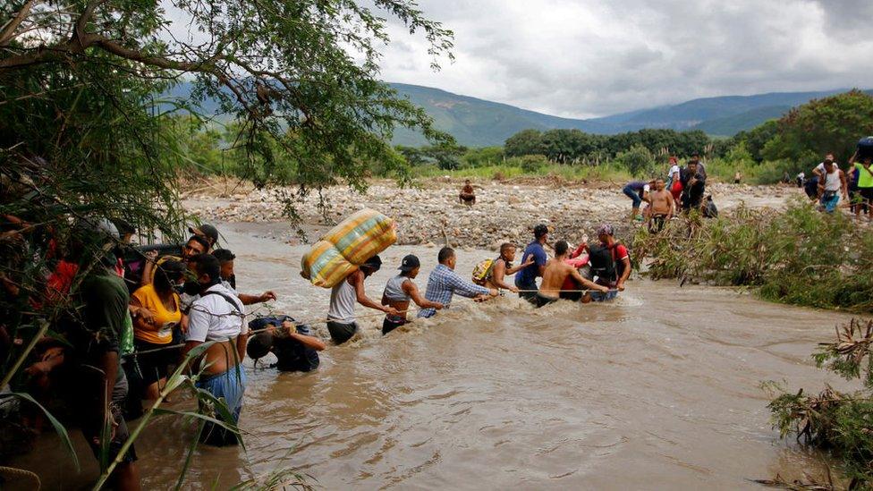 Migrants use a rope to cross the Tachira river, the natural border between Colombia and Venezuela, as the official border remains closed due to the COVID-19 pandemic in Cucuta, Colombia, on November 19, 2020.