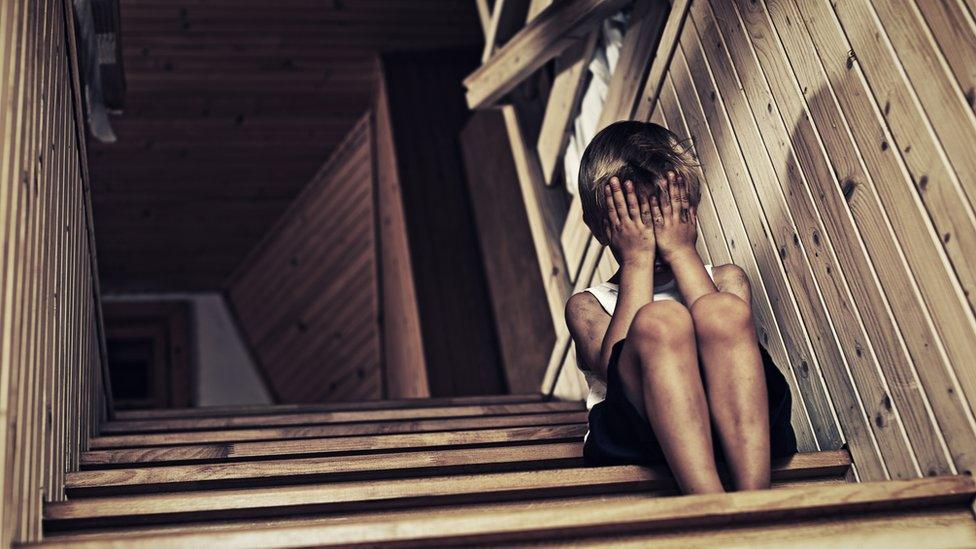 Child sitting on stairs with his head in his hands