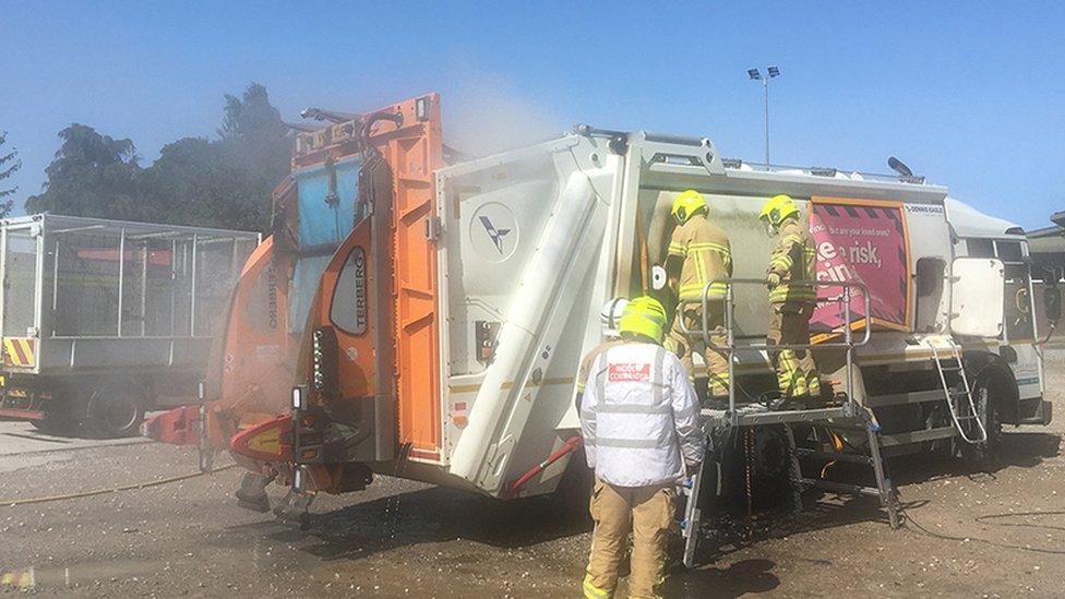 Firefighters putting out a bin lorry fire