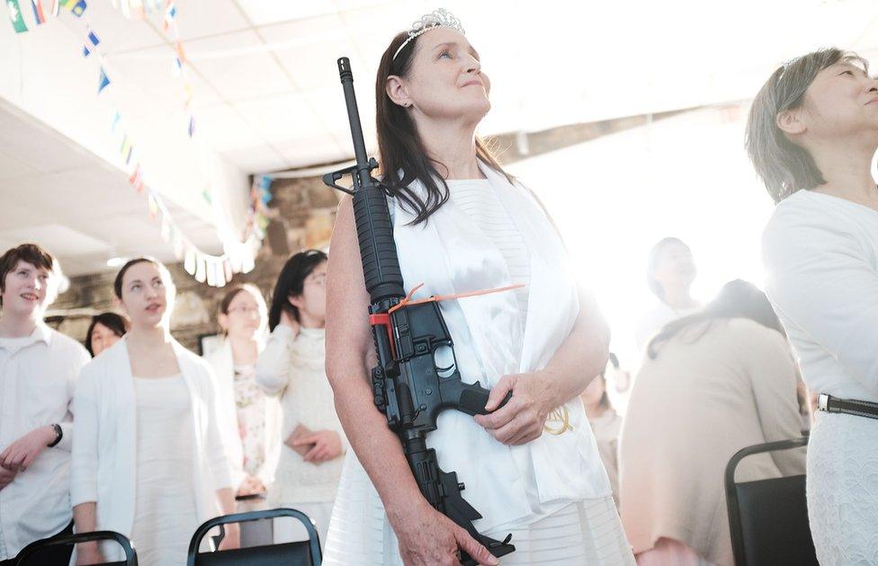 A woman holds an AR-15 rifle during a ceremony at the World Peace and Unification Sanctuary on February 28