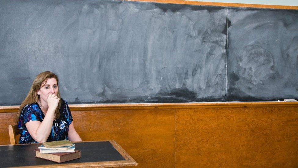 A teacher sitting by a black board