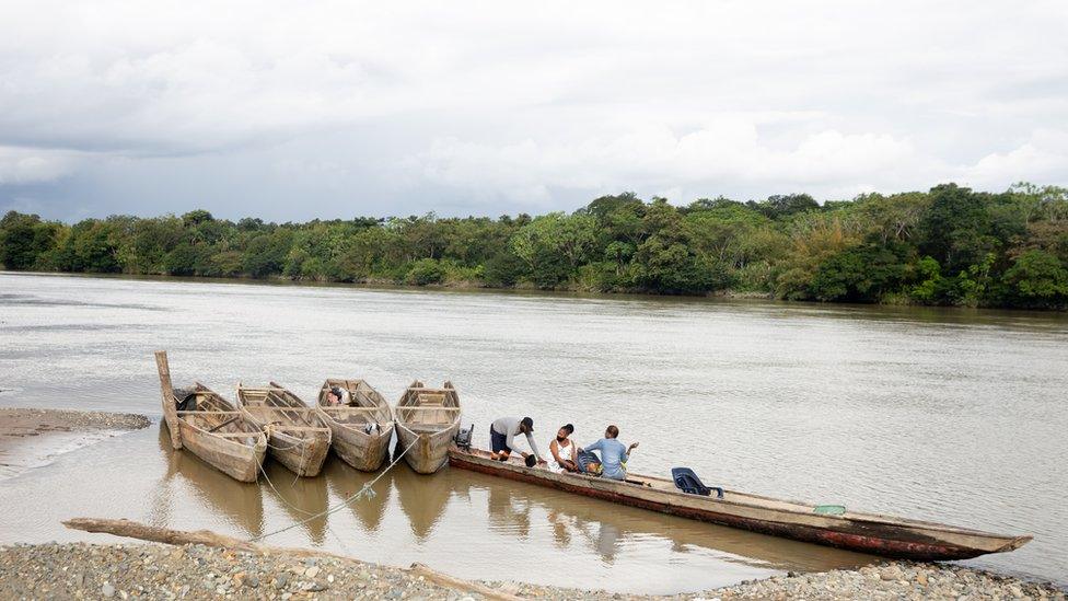 People board a wooden canoe on the Atrato river