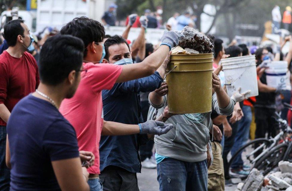 A chain of young men pass buckets of rubble down the line