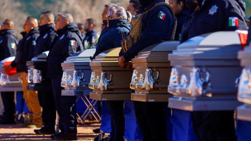 Members of the security forces stand next to the coffins of the prison guards killed in Sunday's prison break in Ciudad Juárez, Mexico