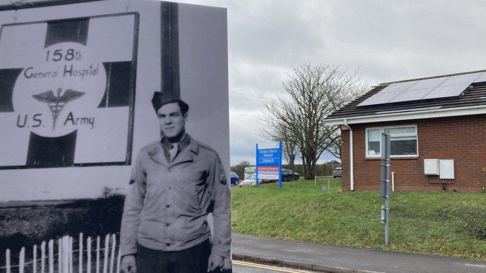 An old black and white picture is held in front of a modern view of entrance B of the hospital.