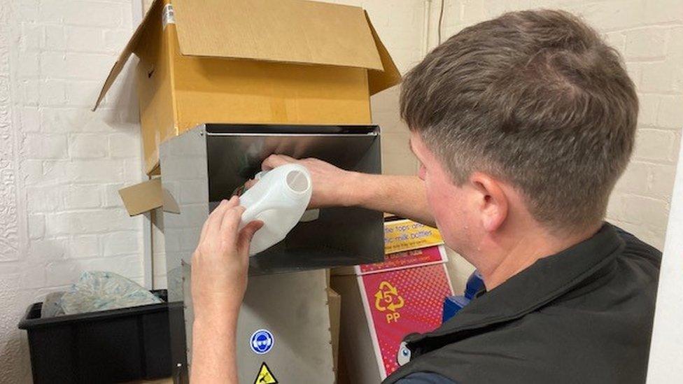 Man putting milk bottle into a crushing machine