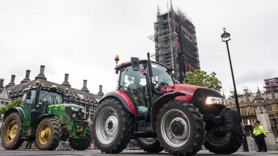 Farmers drive their tractors past the Houses of Parliament, watched by policemen