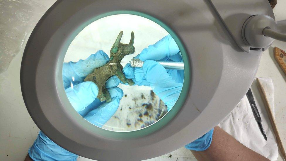 An archaeologist works on a 2,500-year-old bronze bull idol that was unearthed at the archaeological site of Olympia, Greece, 26 February 2021