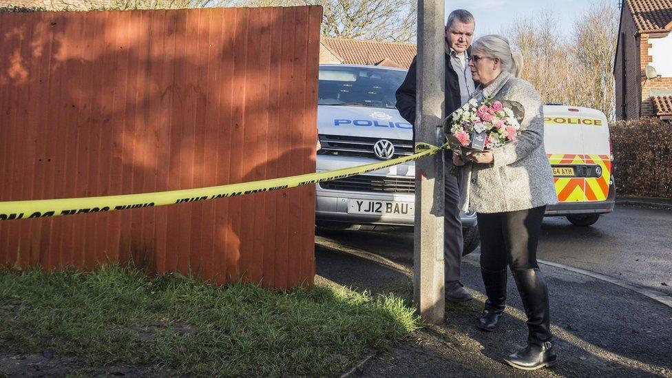 The grandmother of the young victim leaves a floral tribute at the scene near Alness Drive