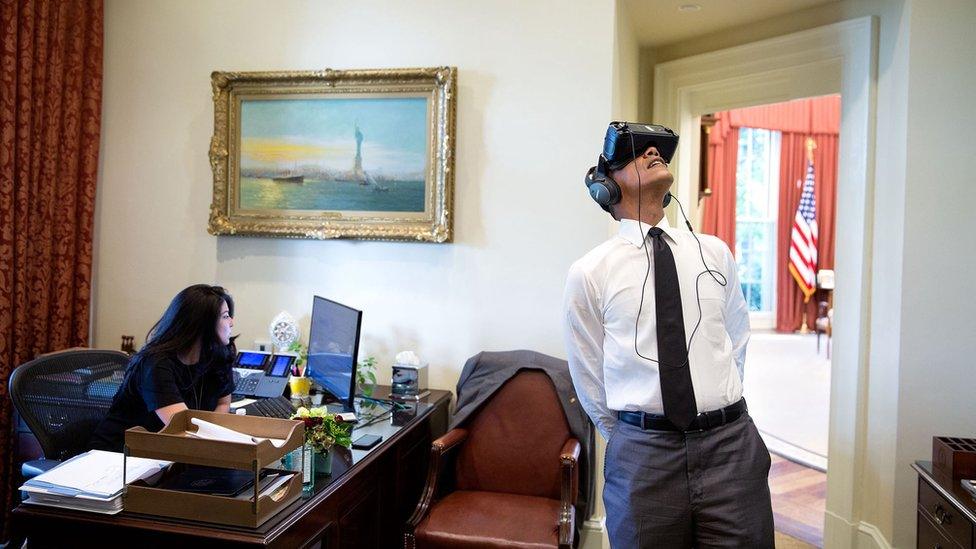 Just outside the Oval Office, Barack Obama looks to the ceiling, wearing a virtual reality headset over his eyes and ears, as a staff member ignores him and works on her computer.